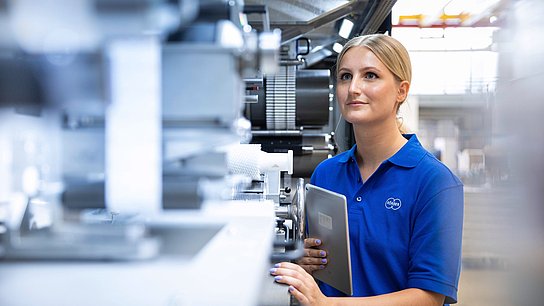 A Körber employee stands at a machine from Körber Technologies. 